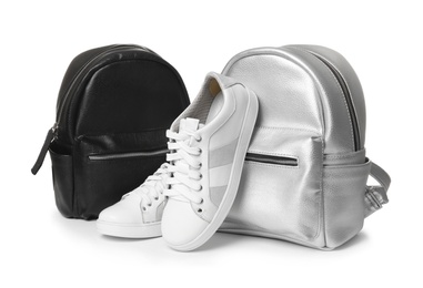 Pair of modern shoes and stylish backpacks on white background
