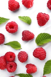 Photo of Tasty ripe raspberries and green leaves on white background, flat lay