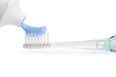 Photo of Squeezing toothpaste onto electric toothbrush isolated on white, closeup