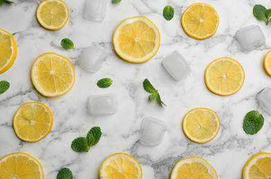 Lemonade layout with juicy lemon slices, mint and ice cubes on white marble table, top view