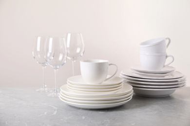 Photo of Set of clean tableware on light grey marble table