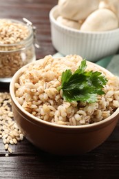 Photo of Delicious pearl barley with parsley in bowl on wooden table, closeup