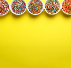 Photo of Colorful sprinkles in bowls on yellow background, flat lay with space for text. Confectionery decor