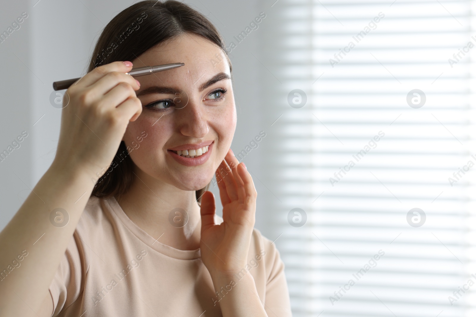 Photo of Smiling woman drawing freckles with pen indoors. Space for text