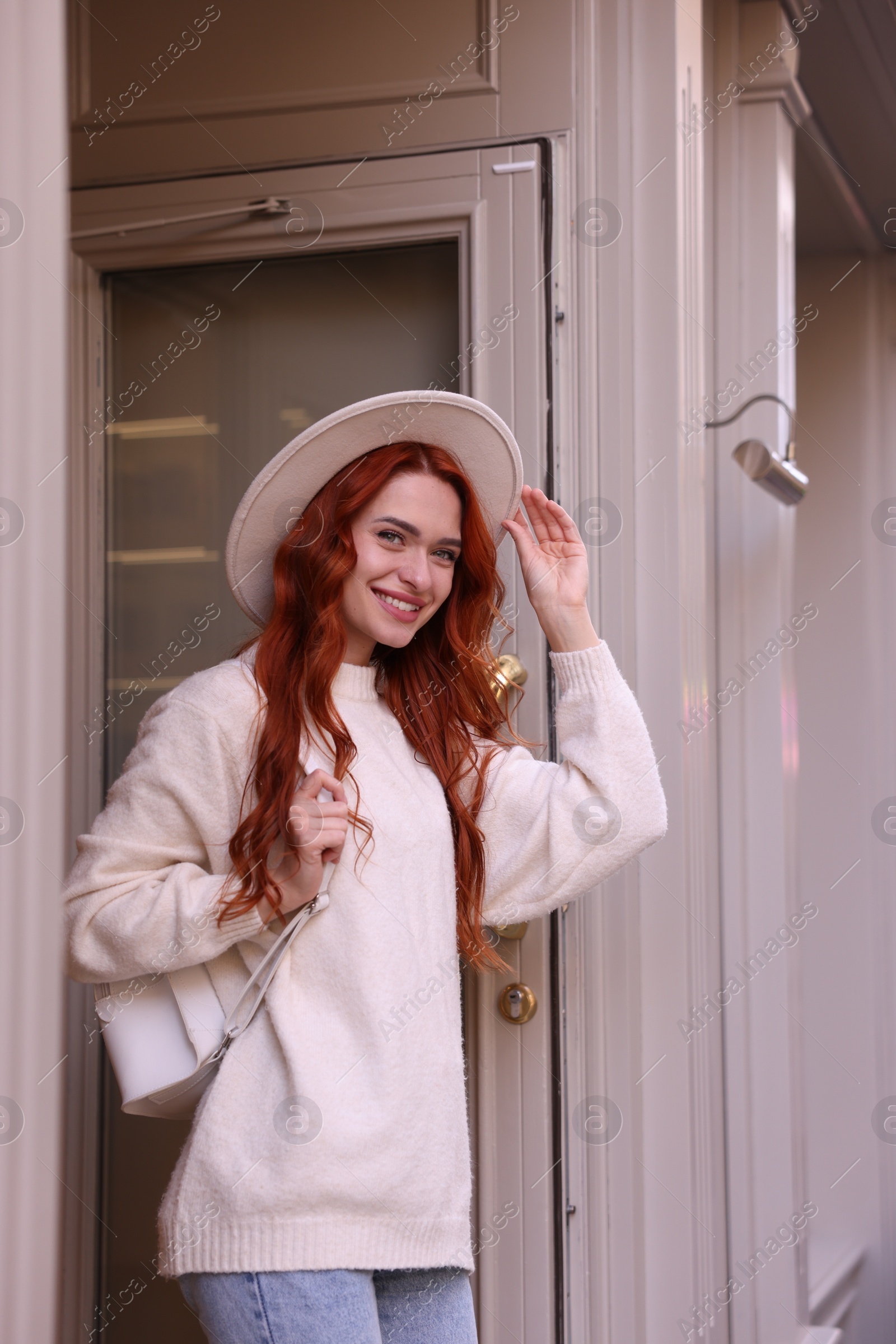 Photo of Smiling woman in hat near building outdoors