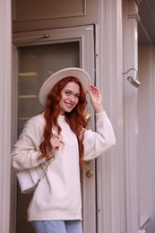 Smiling woman in hat near building outdoors