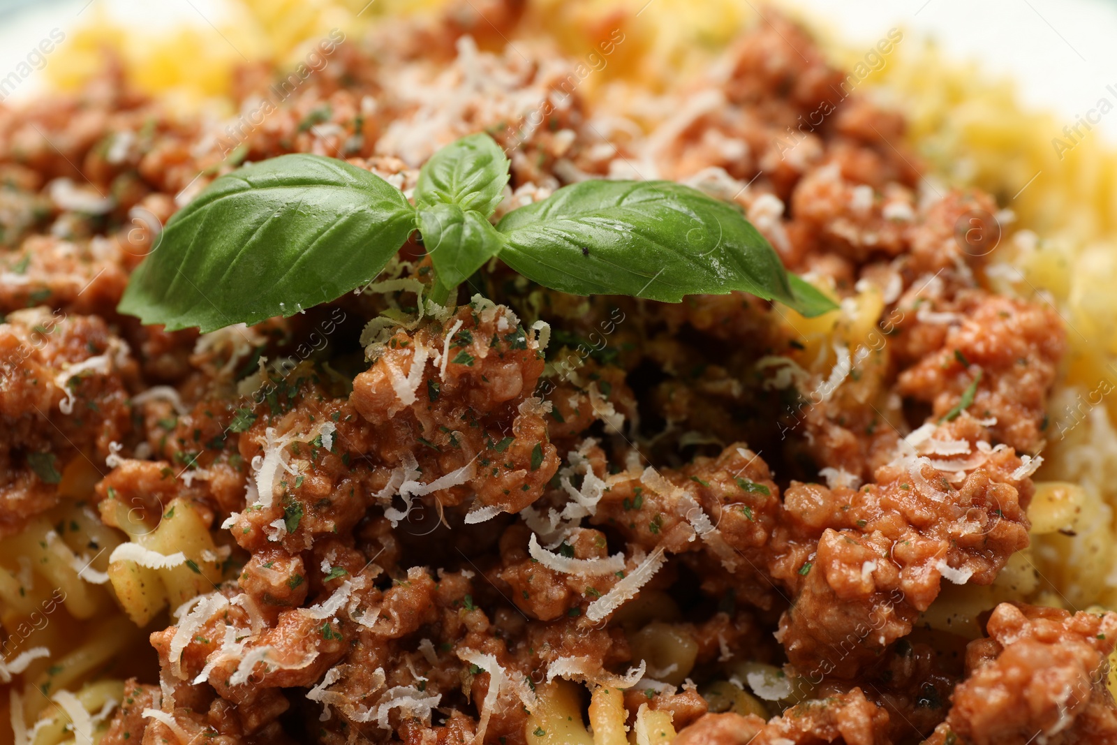 Photo of Delicious pasta with minced meat, basil and parmesan cheese as background, closeup