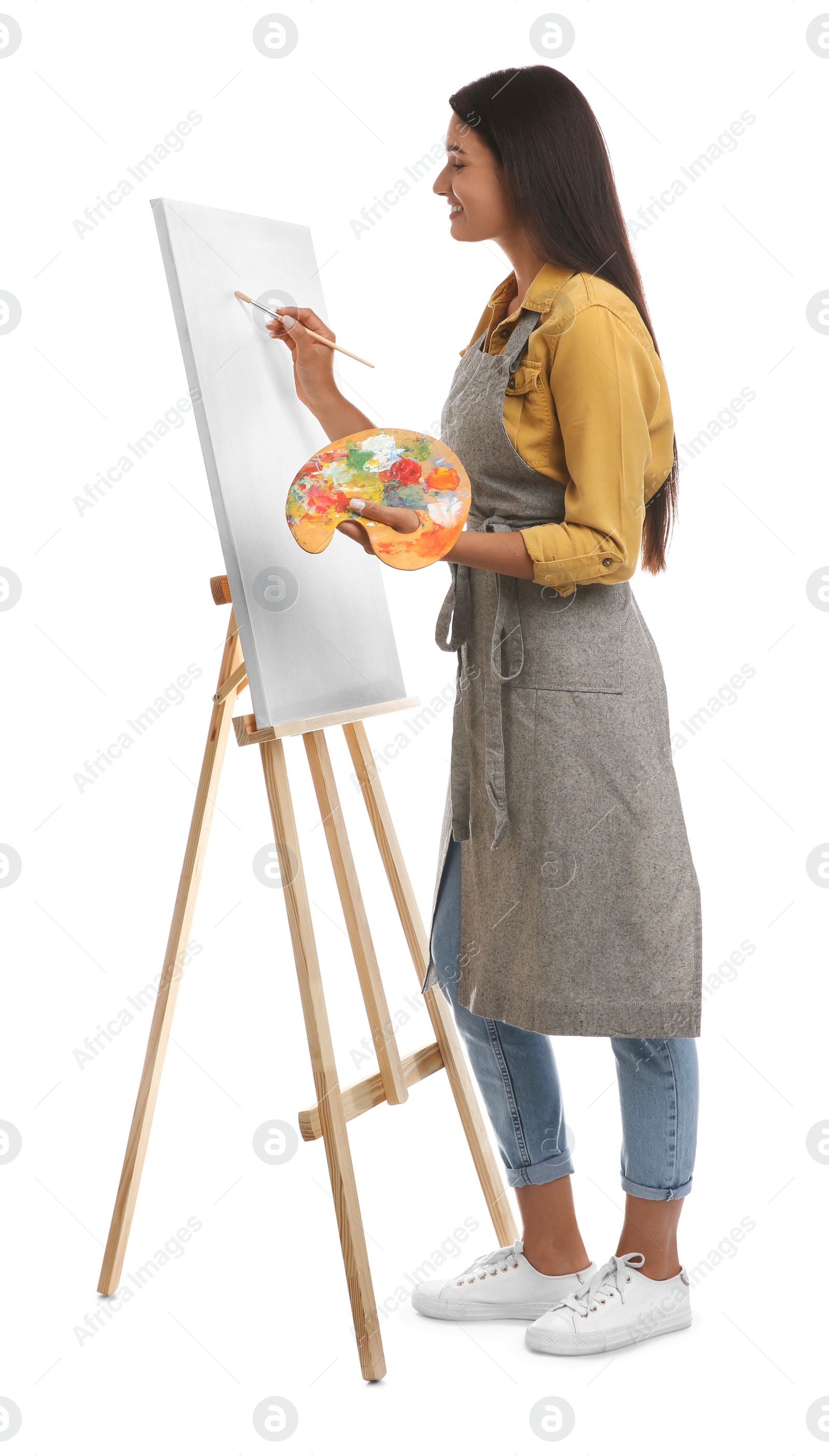 Photo of Young woman drawing on easel against white background