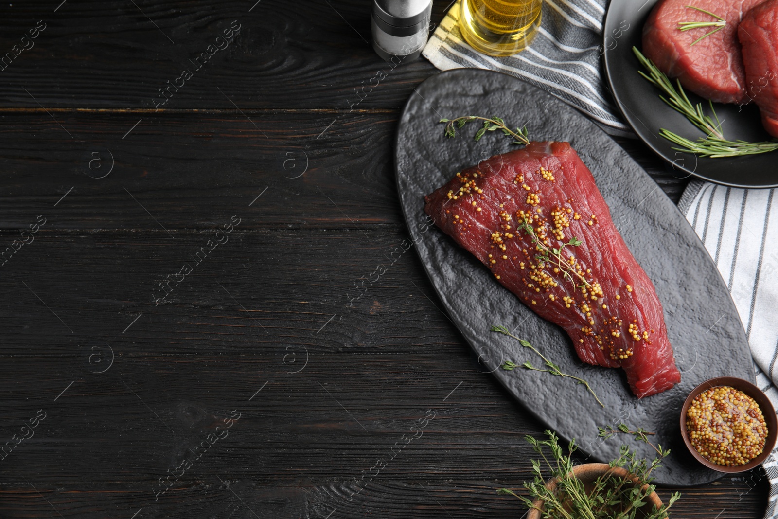 Photo of Flat lay composition with fresh beef cut on black wooden table. Space for text