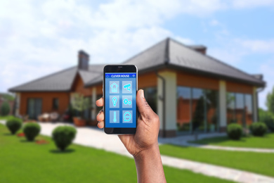 Image of African-American man using home security app on smartphone at backyard, closeup