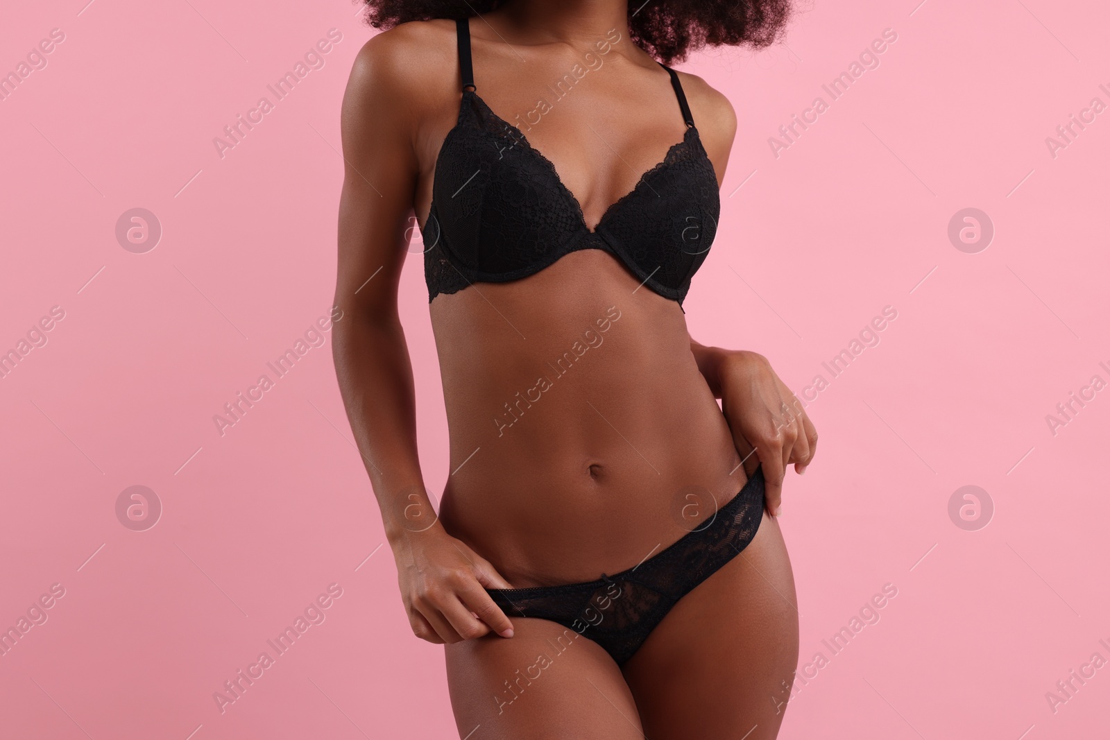 Photo of Woman in elegant black underwear on pink background, closeup