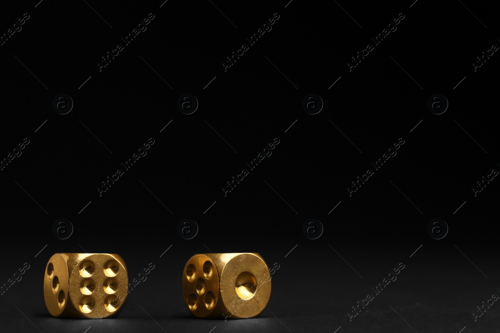 Photo of Gold dices on black background, space for text