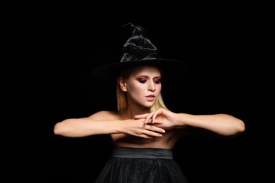 Photo of Witch in black hat on dark background. Scary fantasy character