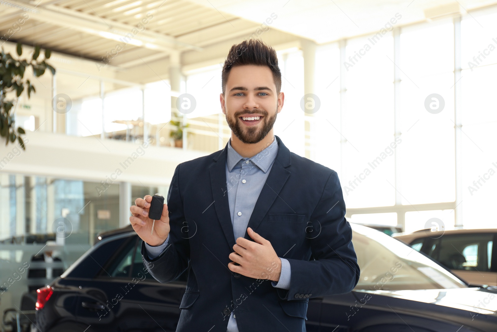 Photo of Salesman with key in modern car salon