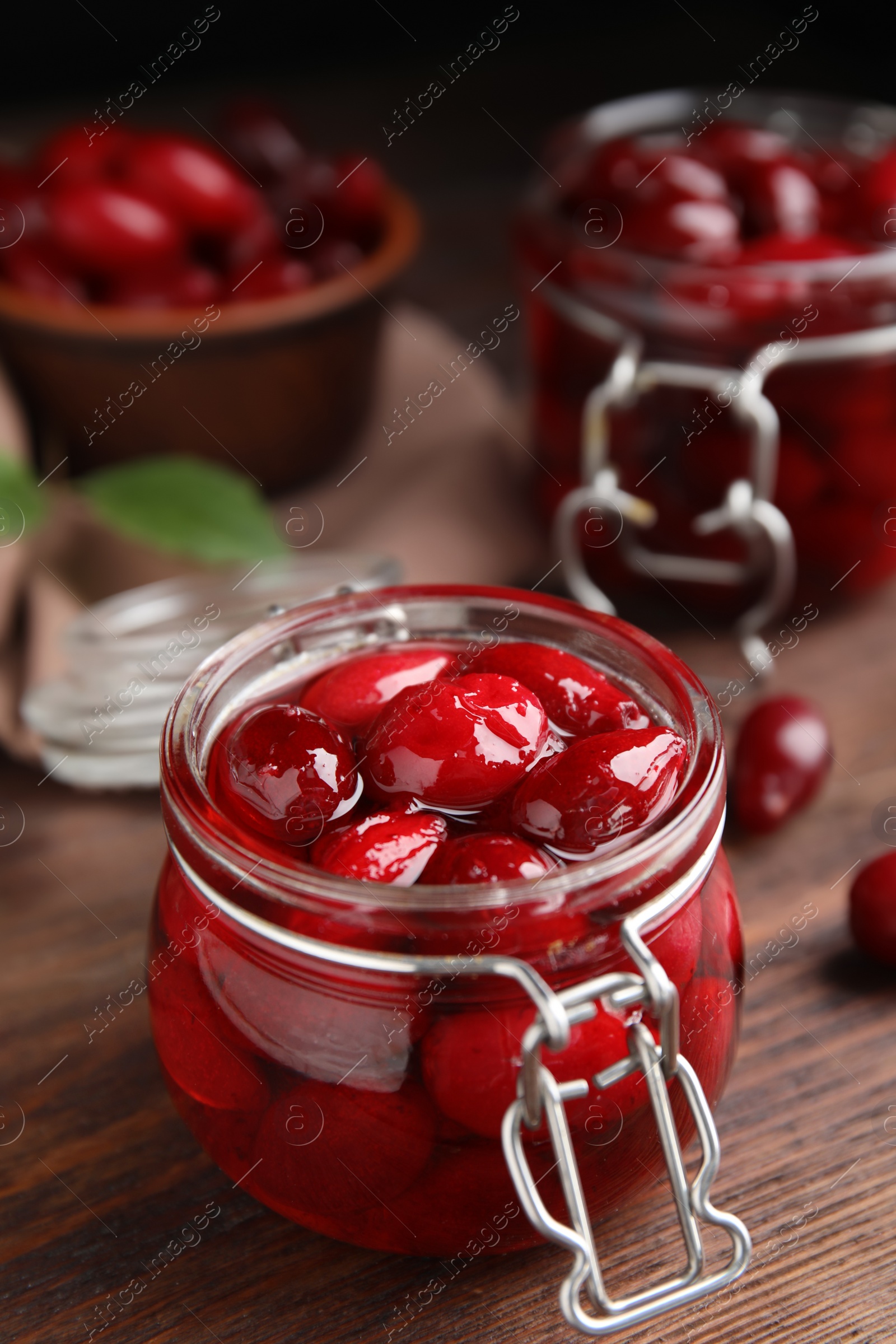 Photo of Delicious dogwood jam with berries in glass jar on wooden table
