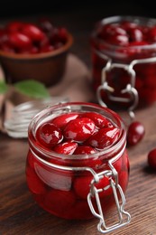 Delicious dogwood jam with berries in glass jar on wooden table