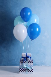 Bunch of color balloons and beautifully wrapped gift boxes on light blue background