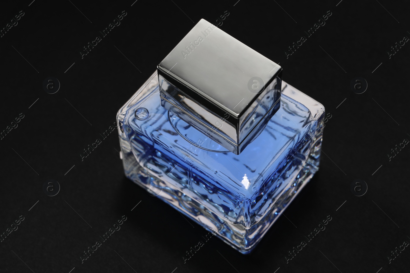 Photo of Blue men's perfume in bottle on black background, closeup