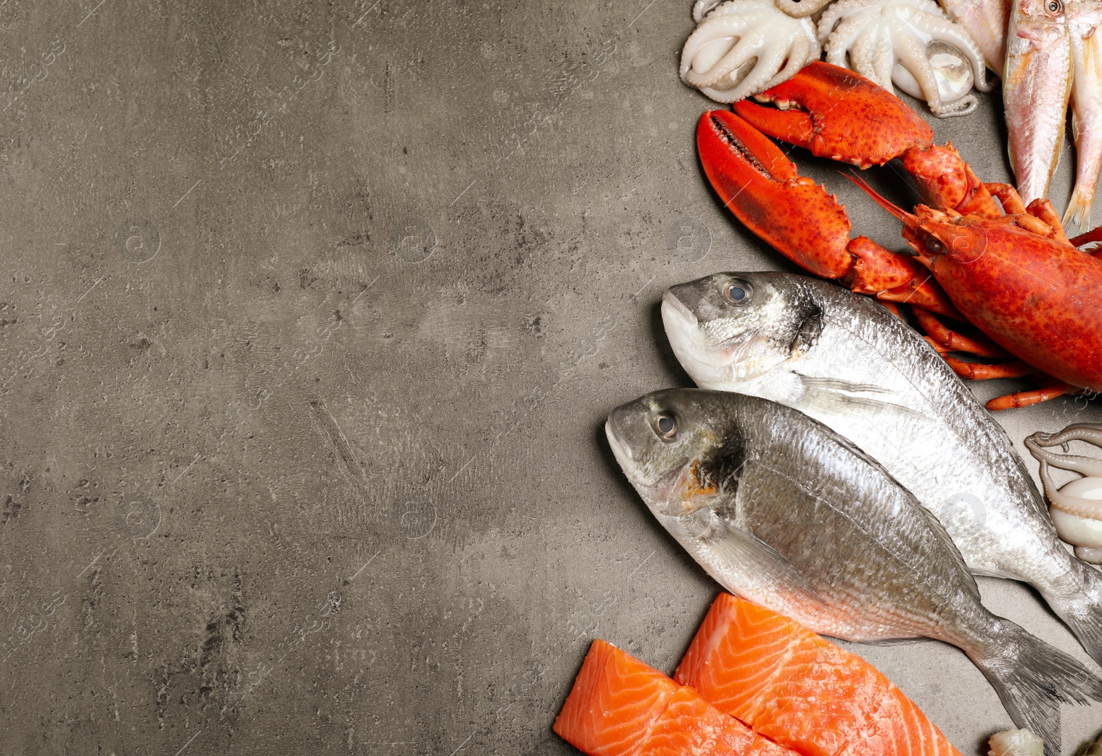 Photo of Fresh fish and seafood on grey table, flat lay. Space for text