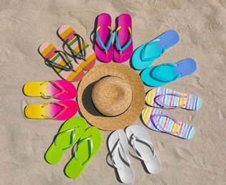 Photo of Flat lay composition with hat and flip flops on sand. Summer beach accessories