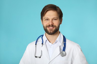 Happy doctor or medical assistant (male nurse) with stethoscope on turquoise background