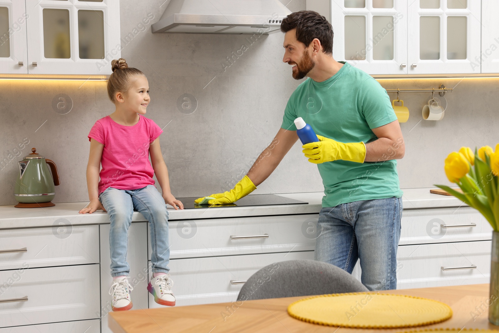 Photo of Spring cleaning. Father and daughter tidying up stove in kitchen together