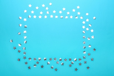 Photo of Frame made of confetti stars with space for text on blue background, top view. Christmas celebration