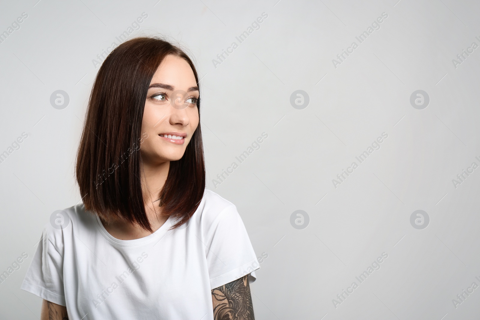 Photo of Portrait of pretty young woman with gorgeous chestnut hair and charming smile on light background, space for text