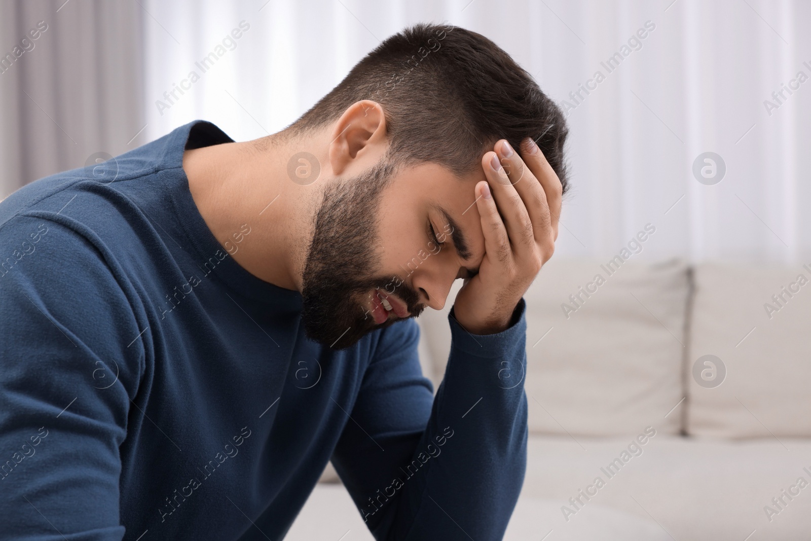 Photo of Unhappy man suffering from headache at home