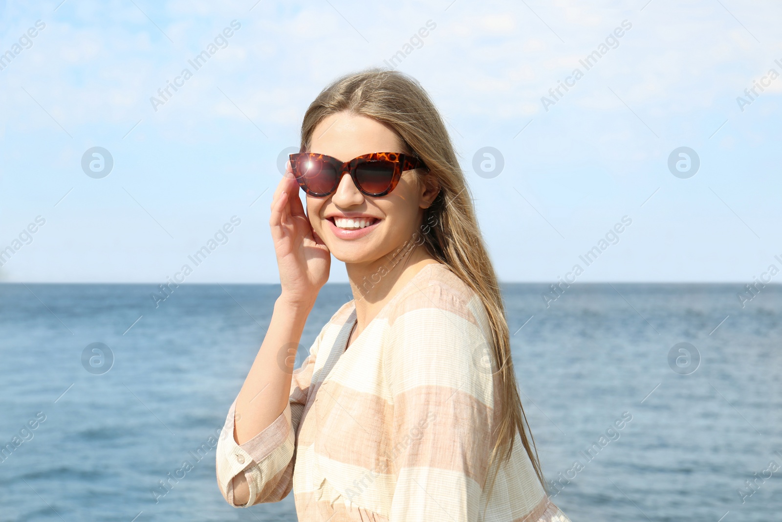 Image of Young woman wearing stylish sunglasses near river