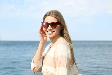 Image of Young woman wearing stylish sunglasses near river