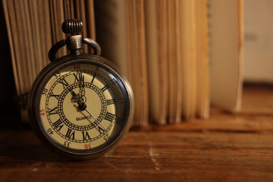Photo of Pocket clock on wooden table, closeup. Space for text