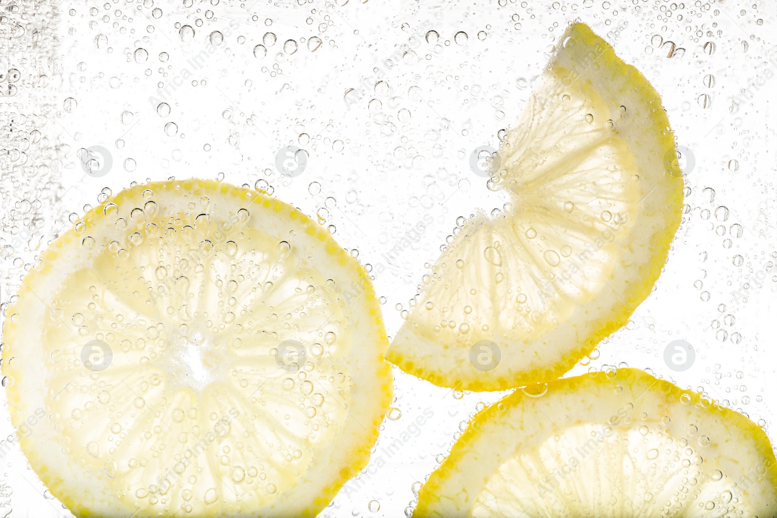 Photo of Juicy lemon slices in soda water against white background, closeup