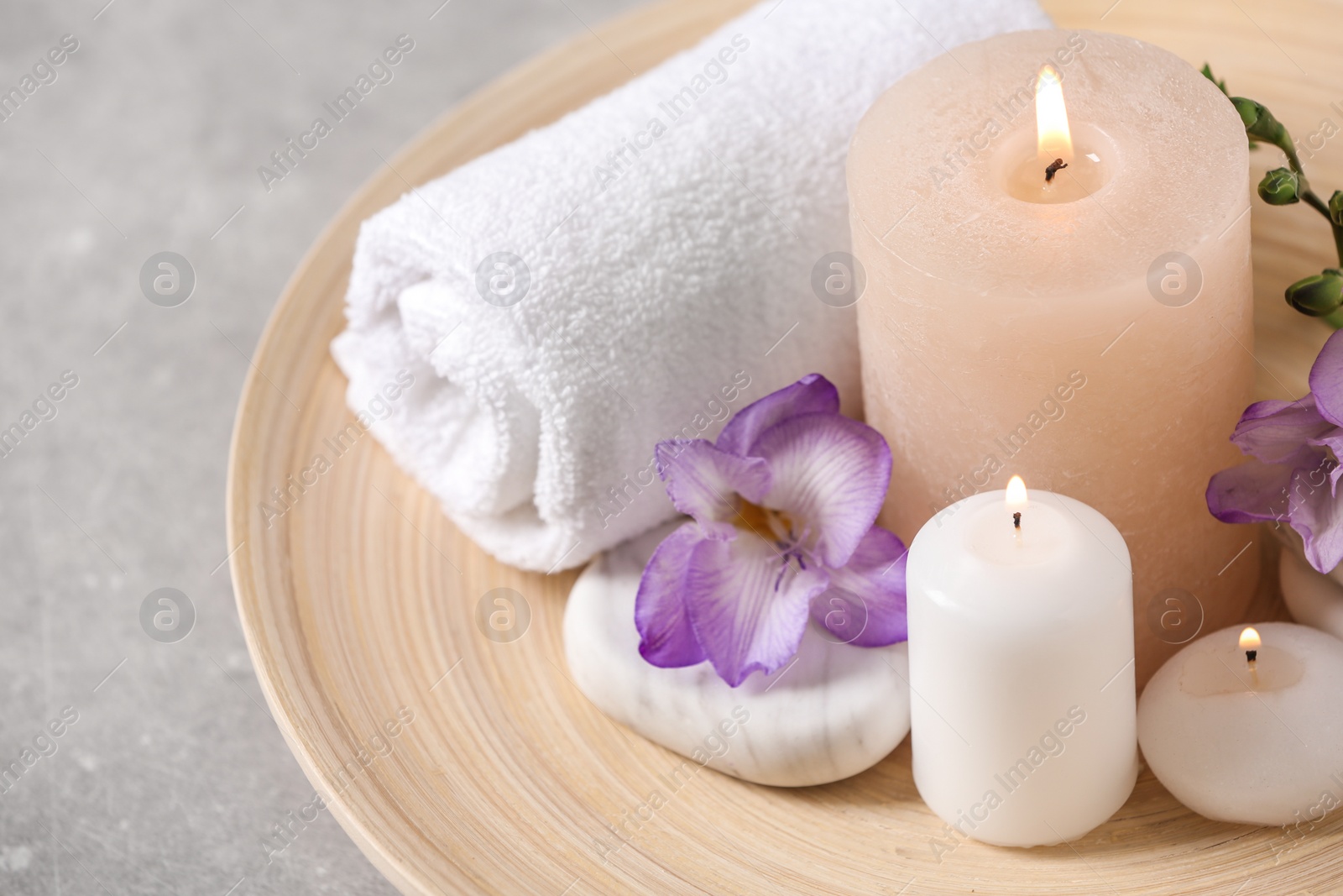 Photo of Beautiful composition with spa stones and burning candles on grey table, closeup