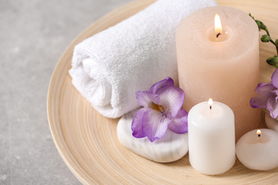 Photo of Beautiful composition with spa stones and burning candles on grey table, closeup