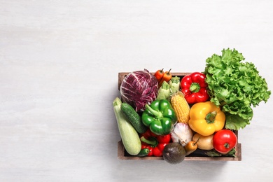 Photo of Crate with different fresh vegetables on light background, top view. Space for text