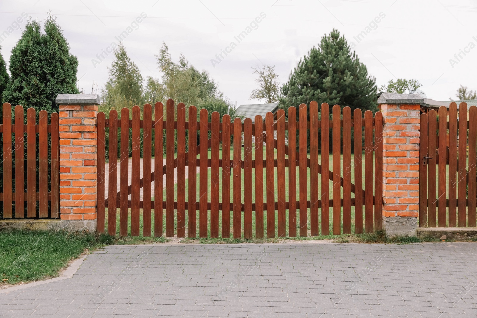 Photo of Wooden brown gates near beautiful trees and lawn outdoors