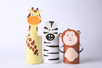 Photo of Toy monkey, giraffe and zebra made from toilet paper hubs on white background. Children's handmade ideas