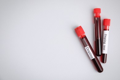 Photo of Test tubes with blood samples on light grey background, flat lay and space for text. Doping control