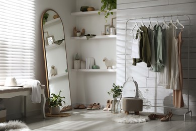 Rack with different stylish clothes, shoes and decorative elements in dressing room. Interior design