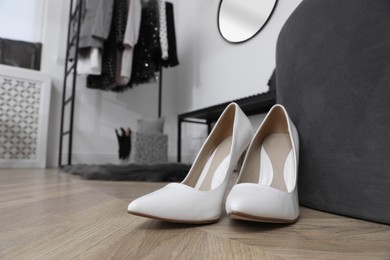 Photo of Elegant high heeled shoes on wooden floor in dressing room