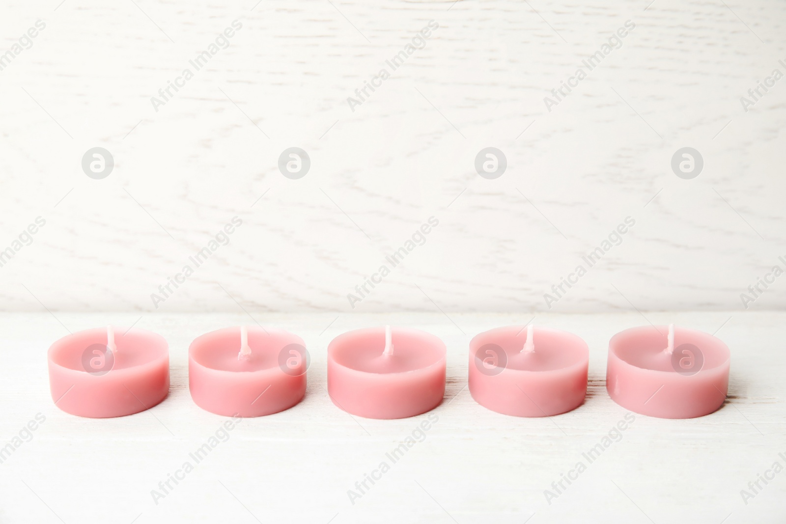 Photo of Pink wax candles on white table, space for text