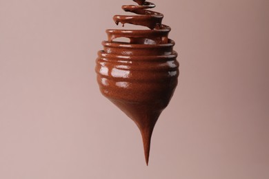 Photo of Chocolate cream flowing from whisk on light background, closeup