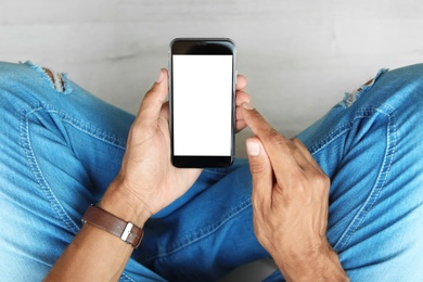 Young man holding mobile phone with blank screen, closeup