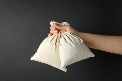 Photo of Woman holding full cotton eco bags on black background, closeup