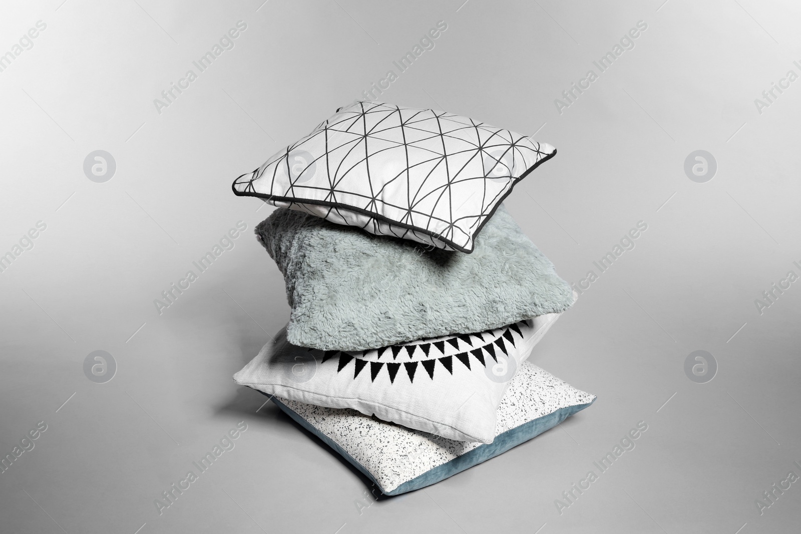 Photo of Stylish decorative pillows stacked on light background