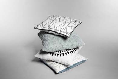 Stylish decorative pillows stacked on light background