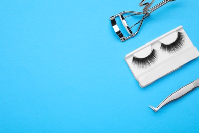 Photo of Flat lay composition with fake eyelashes and tools on light blue background. Space for text