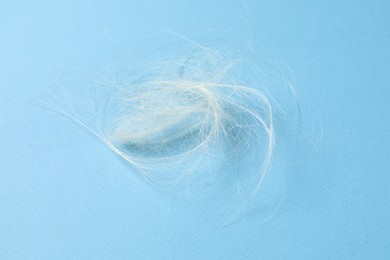 Photo of Pile of lost hair on light blue background