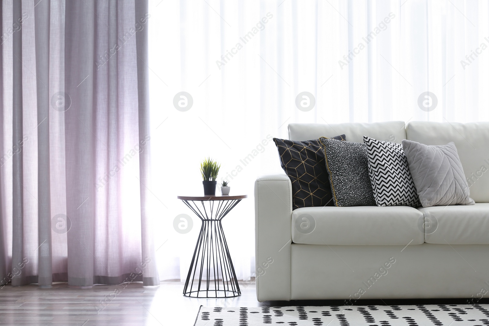 Photo of Comfortable sofa near window with elegant curtains in room